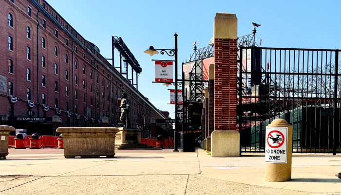 Sign that reads No Drone Zone at Oriole Park at Camden Yards with ballpark and historic Warehouse in background